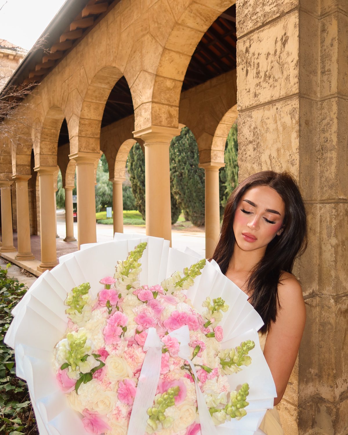 A signature Lili Paris bouquet of pink and white roses, carnations and lisianthus with a pearl bow